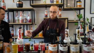 Barmen priprema napitke za šankom sa DOuMIX sirupima, Squeeze bocama i kremovima